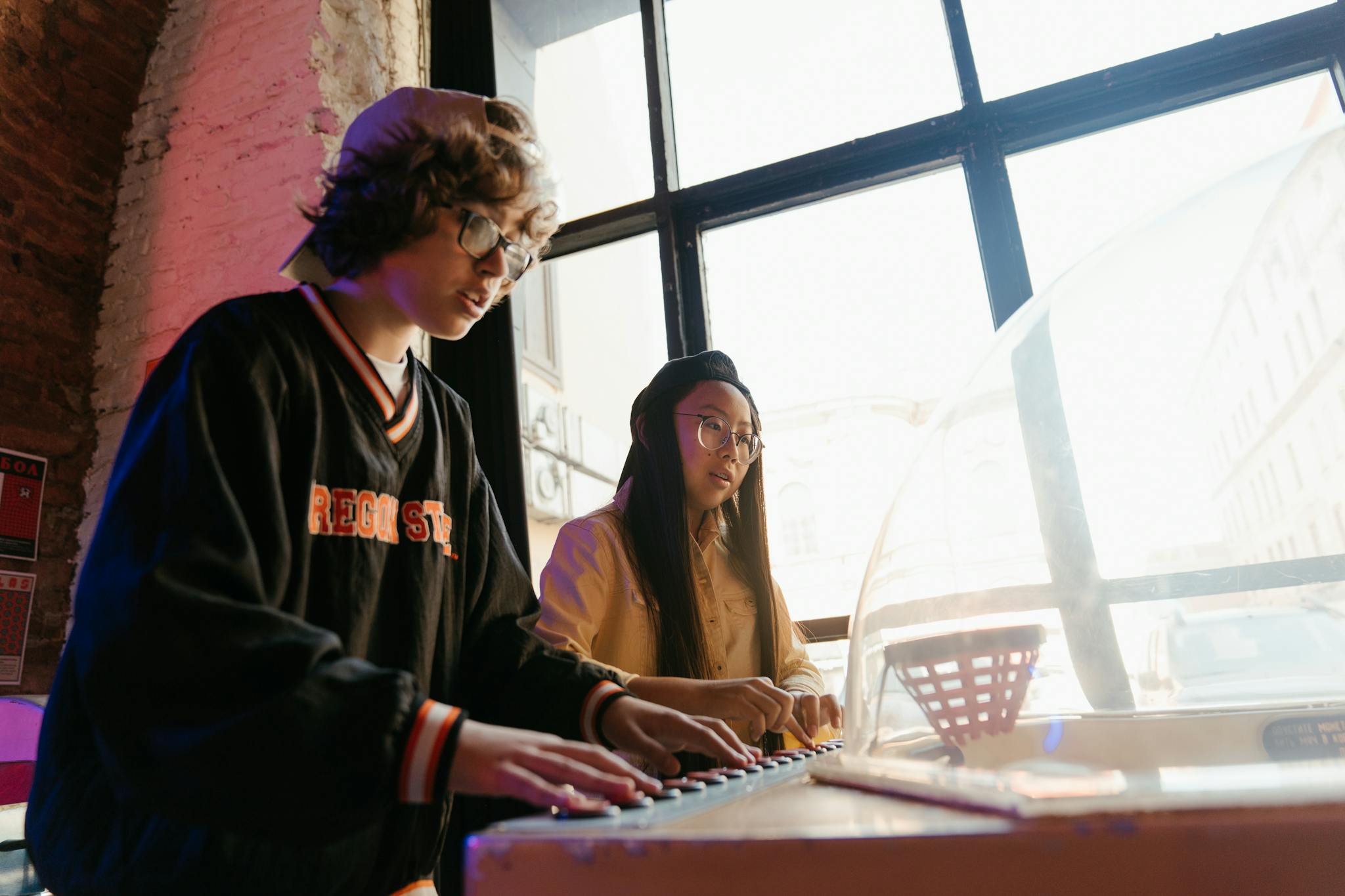 Two teenagers having fun playing an arcade game indoors, showcasing teen spirit and friendship.